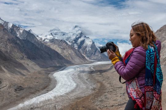 Travelling woman with camera on rang of mountains with snow.