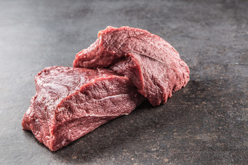 Portion of raw beef shoulder on dark butcher board