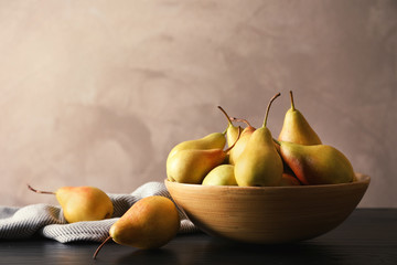Bowl with ripe pears on table against grey background. Space for text