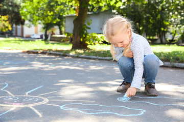 Fototapeta premium Little child drawing with colorful chalk on asphalt. Space for text