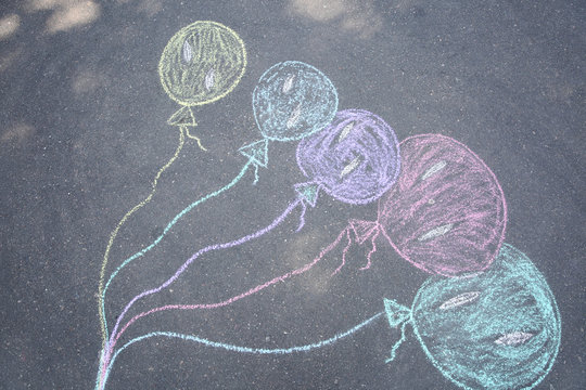 Child's chalk drawing of balloons on asphalt, top view