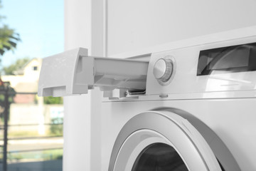 Washing machine with open detergent drawer in laundry room, closeup