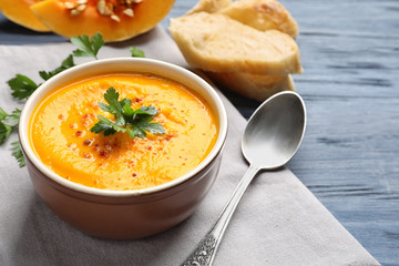 Delicious pumpkin cream soup in bowl on wooden background
