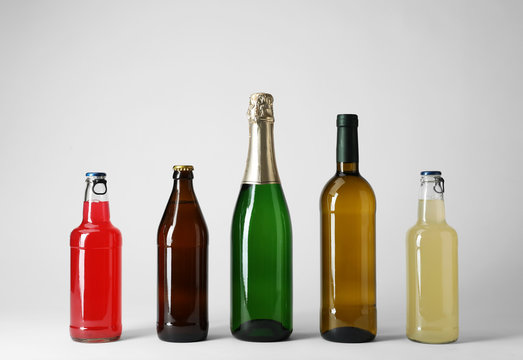 Bottles with different alcoholic drinks on light background