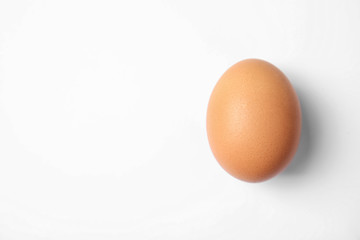 Raw brown chicken egg on white background, top view