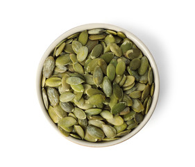 Shelled raw pumpkin seeds in bowl on white background, top view