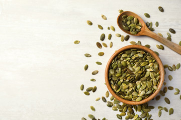 Shelled raw pumpkin seeds on light background, top view. Space for text