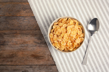 Bowl with healthy cornflakes for breakfast on wooden table, top view. Space for text