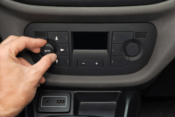 Man adjusting air conditioner in car, closeup