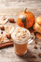 Glass cup with tasty pumpkin spice latte on wooden table