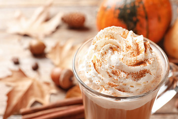 Glass cup with tasty pumpkin spice latte on wooden table, closeup