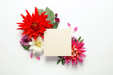 Flat lay composition with beautiful dahlia flowers and blank card on white background