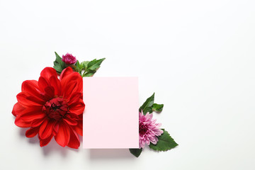 Flat lay composition with beautiful dahlia flowers and blank card on white background