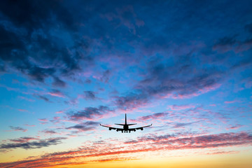 Fototapeta na wymiar Colorful bright sunset with flying airplane silhouette