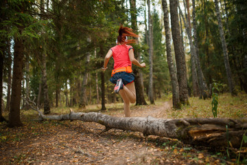 Photo from back of young woman running through forest