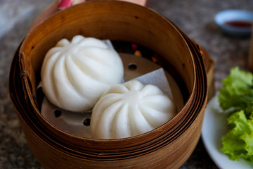 Steamed white flour dumplings placed in a wooden tray on the table.