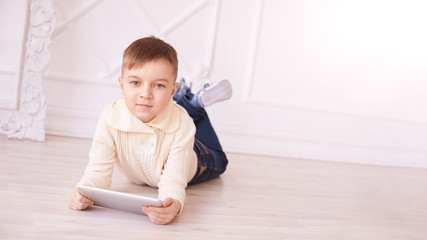 Cute boy. Computer tablet. play game, chat. Training. light interior