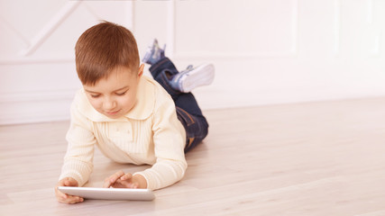 Cute boy. Computer tablet. play game, chat. Training. light interior