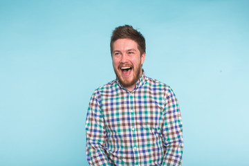 Emotion, people and fun concept - Young handsome man laughing on blue background