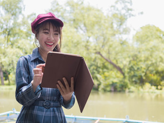 Asian woman relax use tablet to play the Internet to play in the park.