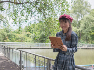 Asian woman relax use tablet to play the Internet to play in the park.