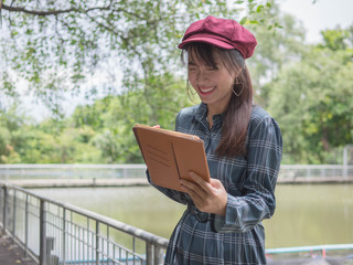 Asian woman relax use tablet to play the Internet to play in the park.
