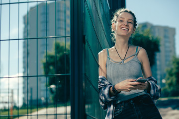 Fototapeta premium Relaxed lady laughing while standing with her smartphone