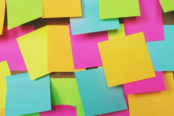 collection of colorful variety. paper note reminder sticky notes pad on cork bulletin board. empty space for text. soft focus.