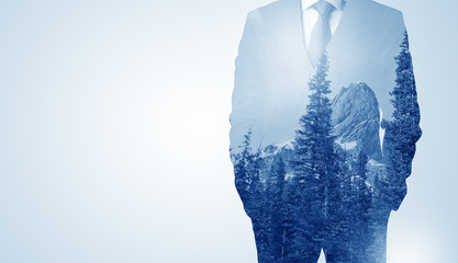 Young businessman standing and meditate with trees on the background 