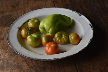 Plato con tomates pequeños y un pimiento del huerto