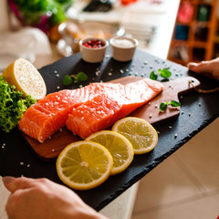 Fresh raw salmon fish served on black stone on wooden table