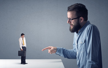Young professional businessman being angry with an other miniature businessman 