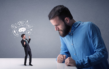 Young professional businessman being angry with an other miniature businessman who has drawn speech...