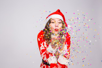 Beautiful girl in Santa's costume welcoming the new year 2019 blowing confetti to camera. New Year celebration and party concept