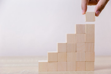 Hand arranging wood block stacking as step stair,With the concept of a thriving business going for success.