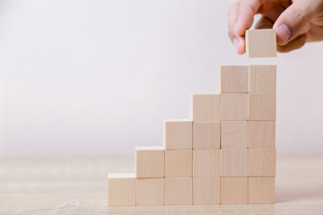 Hand arranging wood block stacking as step stair,With the concept of a thriving business going for success.