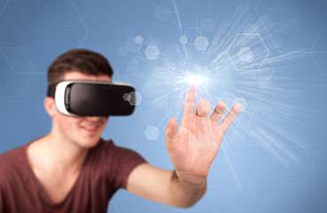 Young impressed man wearing virtual reality goggles with blue hexagons around him 