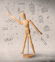 Wooden mannequin posed in front of a greyish background with hobby related scribbles behind it