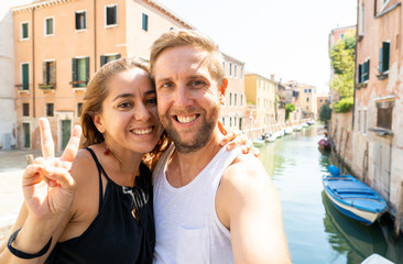 Fototapeta na wymiar Sweet couple in love taking a selfie in Venice Italy while traveling around europe