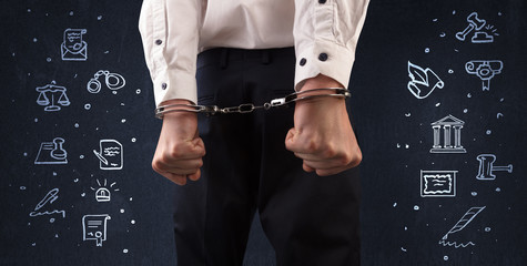 Chalk drawn courthouse symbols and close handcuffed hands in suit
