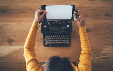 Woman writer setting up vintage typewriter - obrazy, fototapety, plakaty