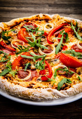 Pizza with pepper,salami and champignon on wooden table