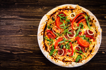 Pizza with pepper,salami and champignon on wooden table