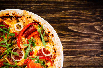 Pizza with pepper,salami and champignon on wooden table