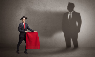 Businessman standing with red cloth on his hand and his shadow on the background

