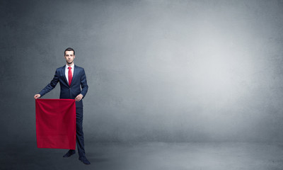 Businessman standing with red toreador cloth in his hand in an empty room
