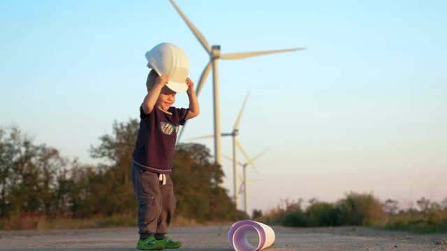 A little boy plays with constructor helmet. He makes sharp moves and then suddenly takes helmet off