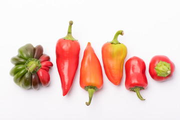 Several ripe sweet and hot peppers of red and orange on a white background