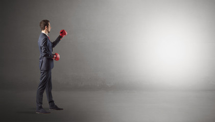 Businessman fighting with boxing gloves in an empty space
