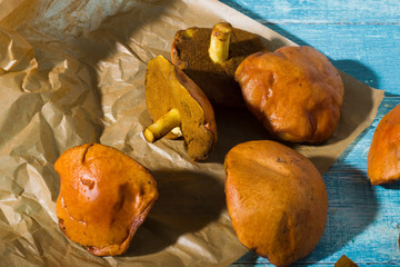 weeping bolete mushrooms on baking paper, old blue wood table